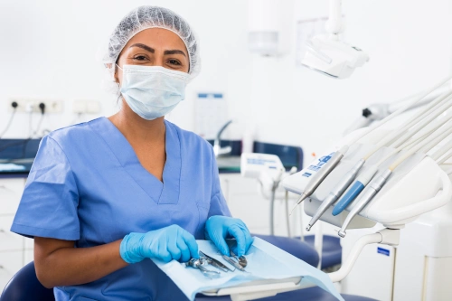 dental assistant with mask smiling while handling dental instruments